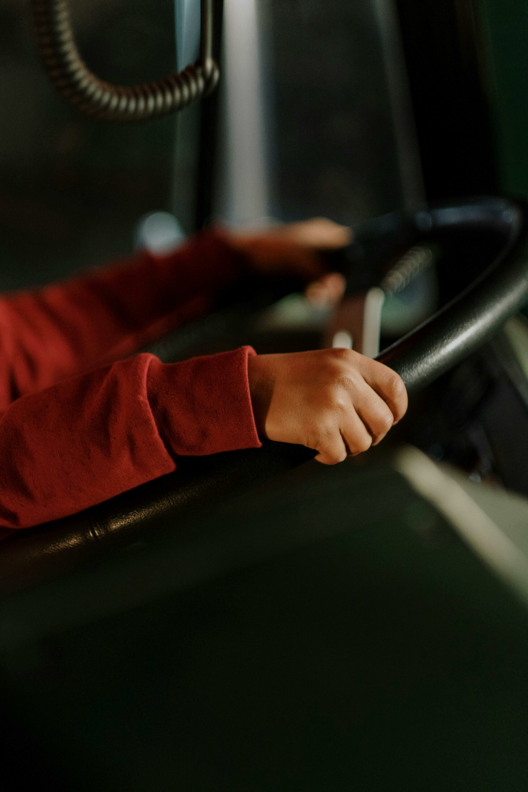 Close view of hands gripping steering wheel inside a vehicle with red sleeves.